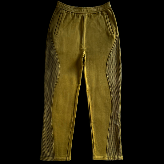 Pair of mustard yellow pants with mesh panels on a black background